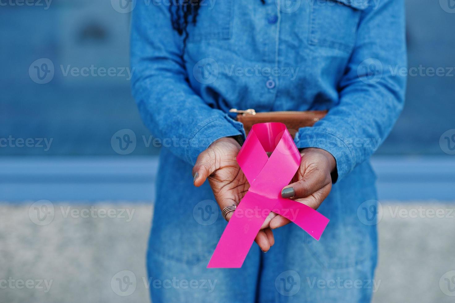 el poder de luchar. elegantes mujeres afroamericanas de moda en jeans usan contra un edificio moderno con cinta rosa para el cáncer de mama. foto