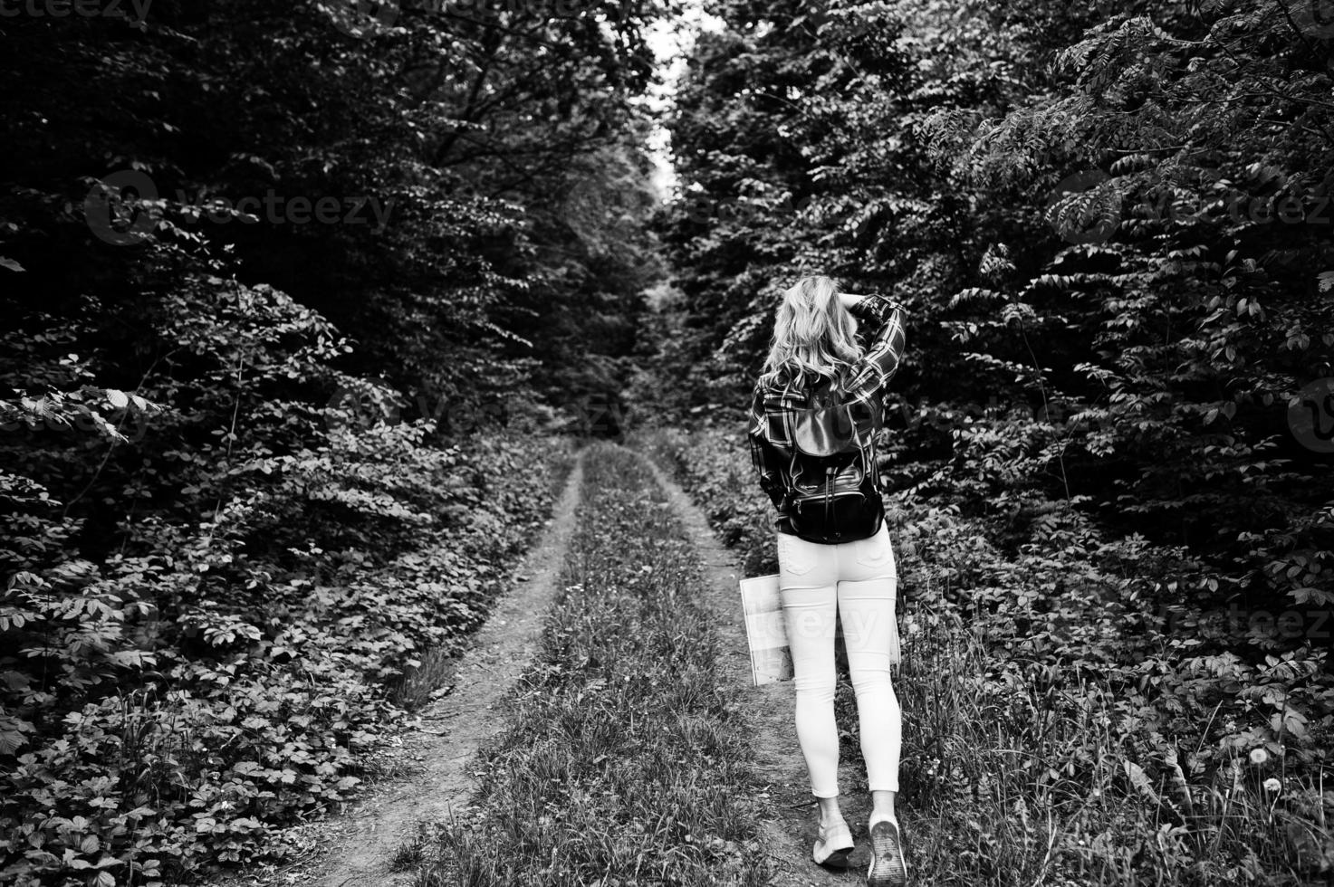 retrato de una joven y hermosa mujer rubia con camisa de tartán sosteniendo un mapa en el bosque. foto