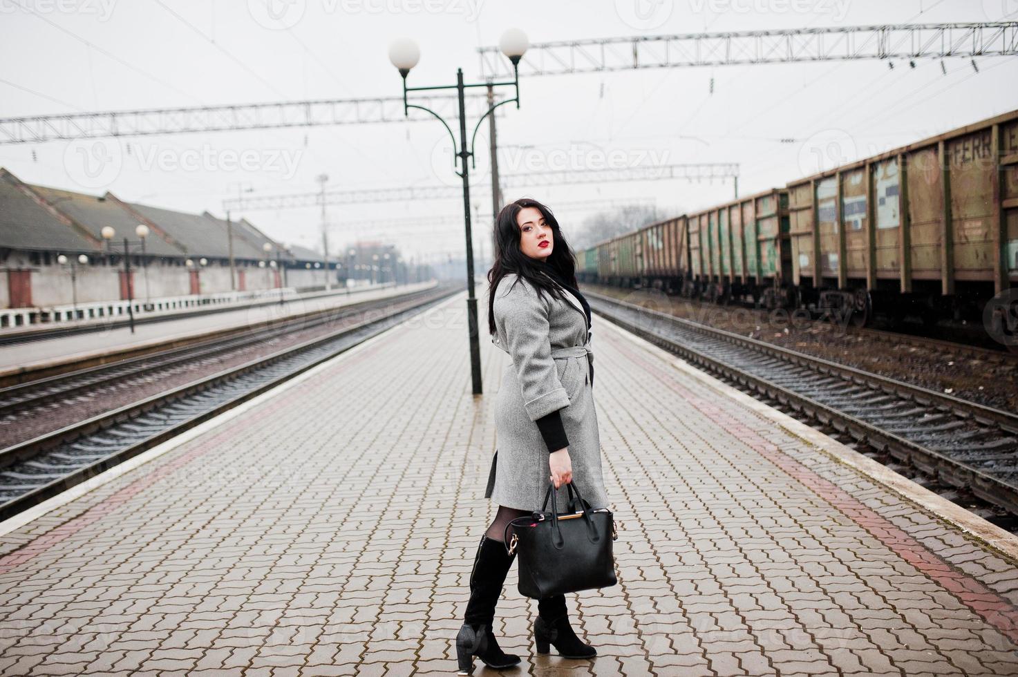 Brunette girl in gray coat posed in railway station. photo