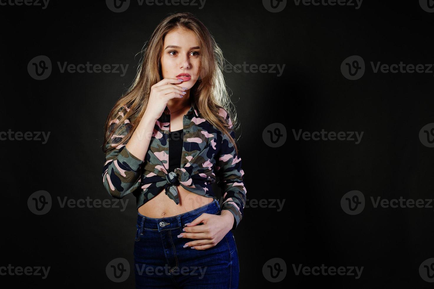 Handsome brunette girl wear military shirt and jeans, posing at studio against gray background. Studio model portrait. photo