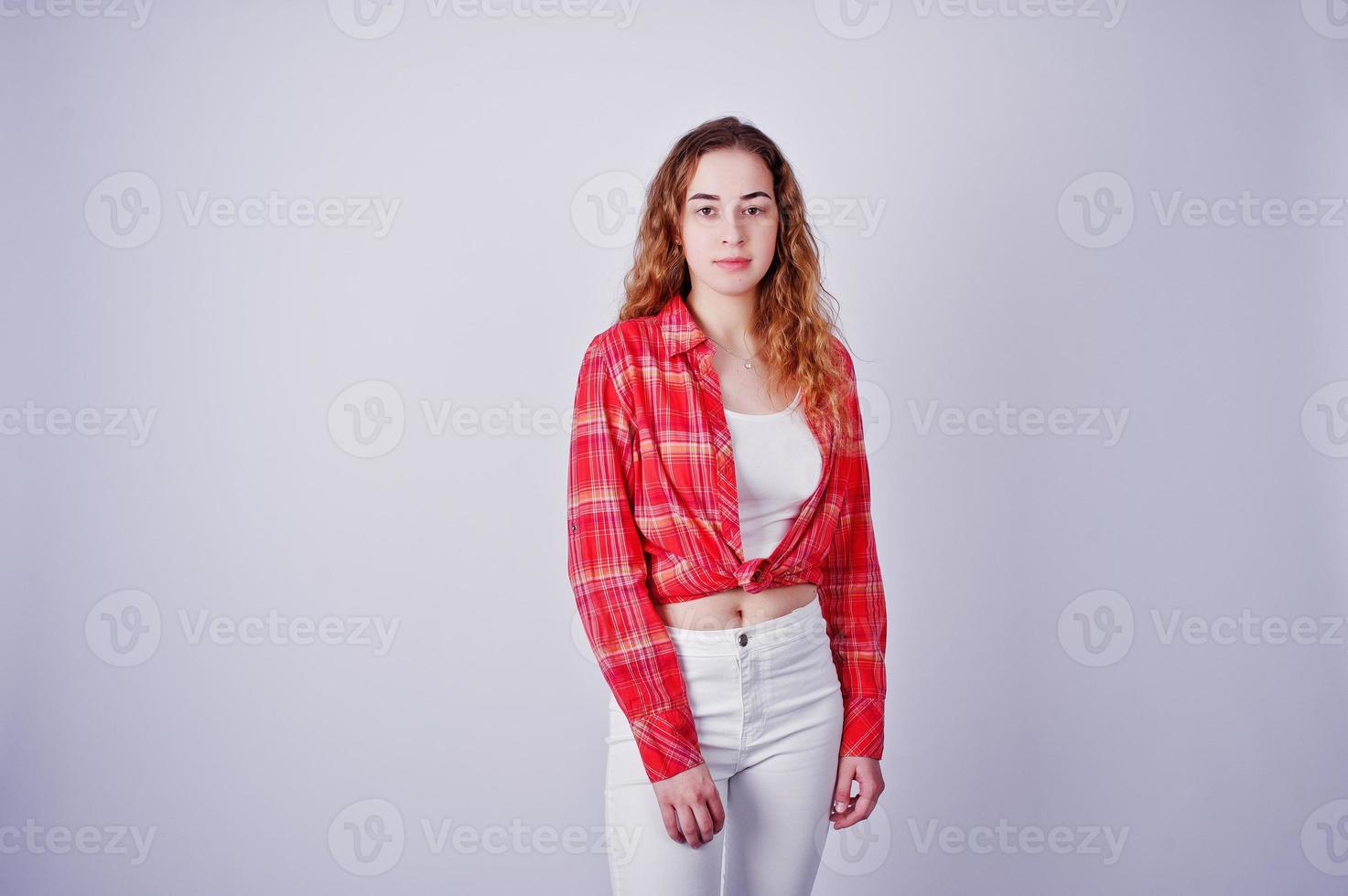 Young girl in red checked shirt and white pants against white background on studio. photo