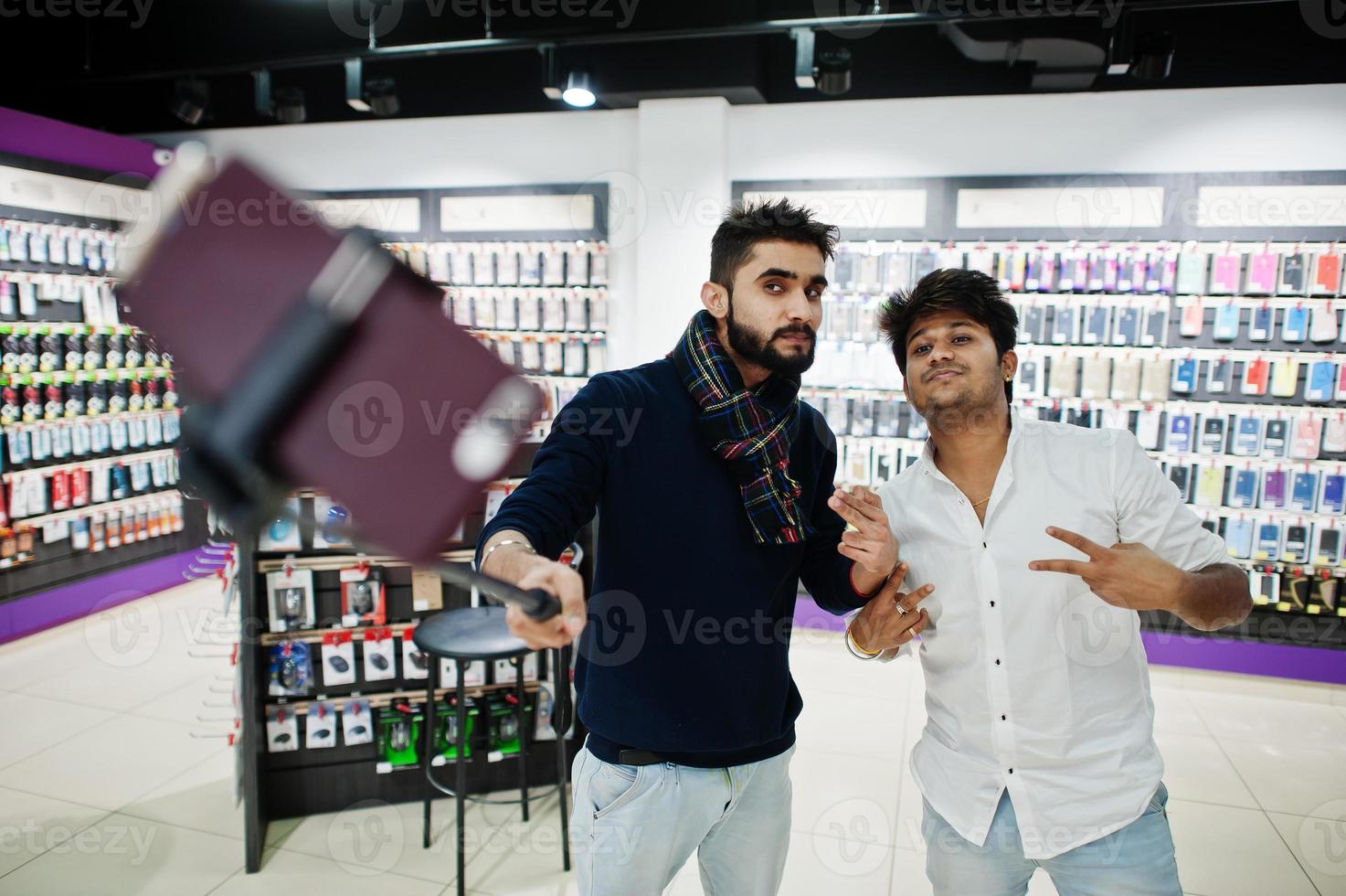 dos indios sirven al comprador del cliente en el teléfono móvil haciendo selfie con un palo monopie. concepto de pueblos y tecnologías del sur de Asia. tienda de celulares foto