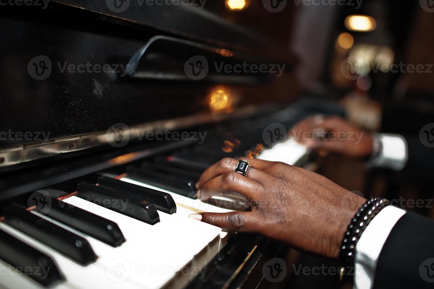 Fingers of african american man in black suit play piano. photo