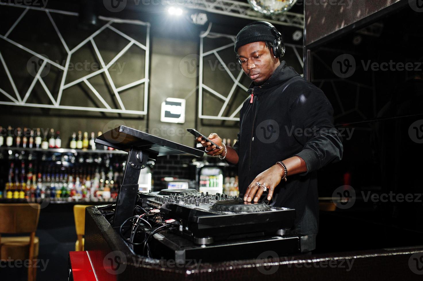 African american dj play music on decks at night club. photo