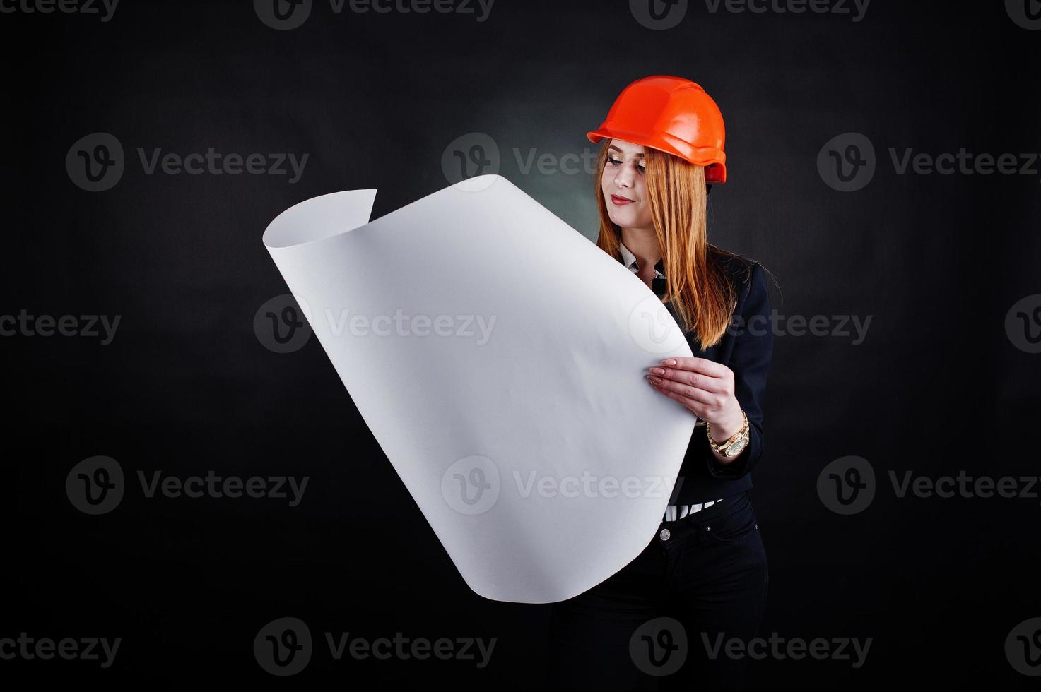 Engineer woman in orange protect helmet with construction paper projekt. photo