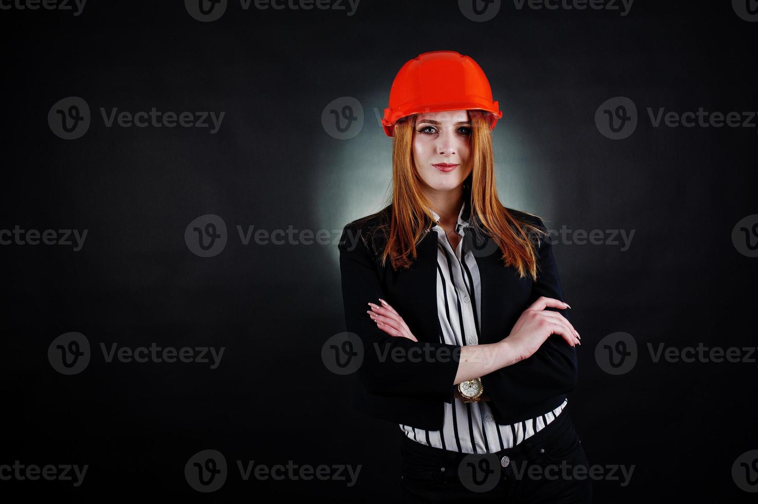 Engineer woman in orange protect helmet on studio black background. photo