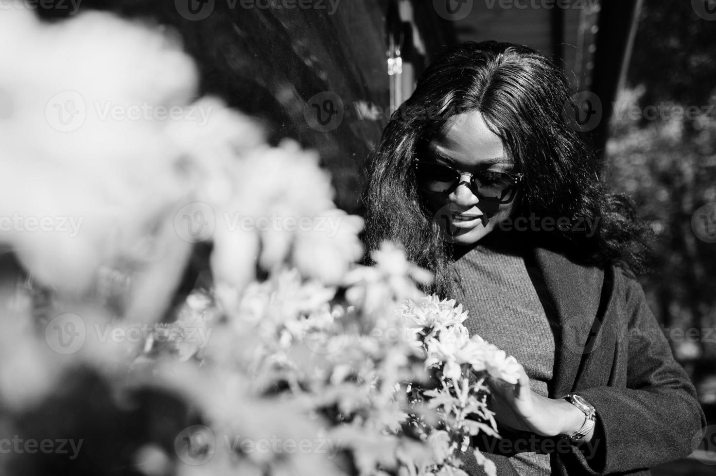 elegante chica afroamericana con abrigo azul y gafas de sol posadas en el soleado día de otoño. mujer modelo africana. foto