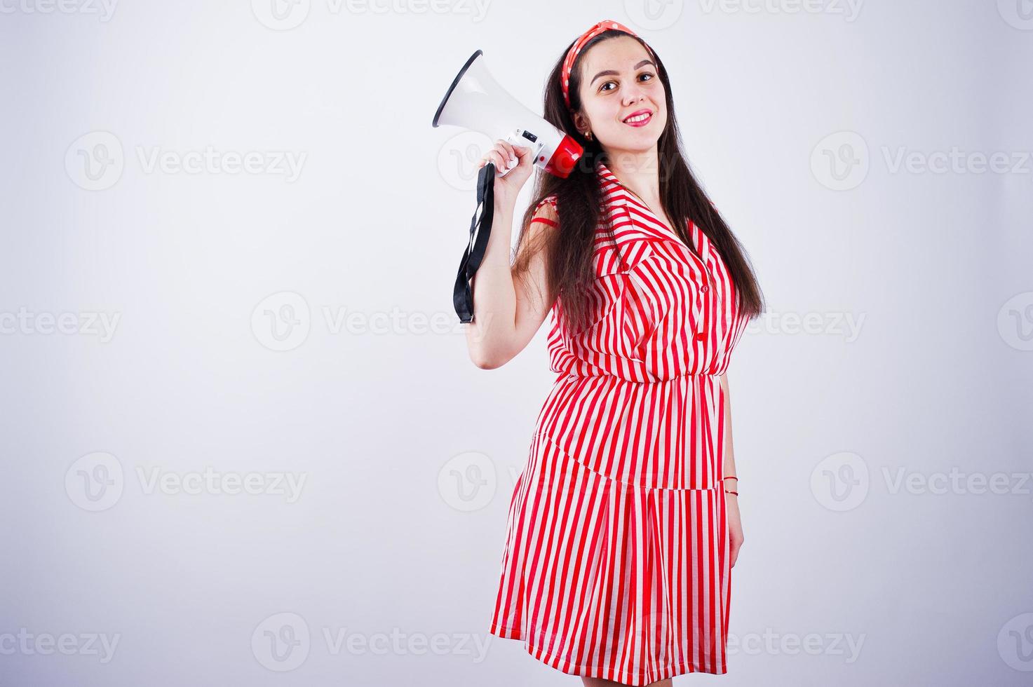 Portrait of a young beautiful woman in red dress talking into megaphone. photo