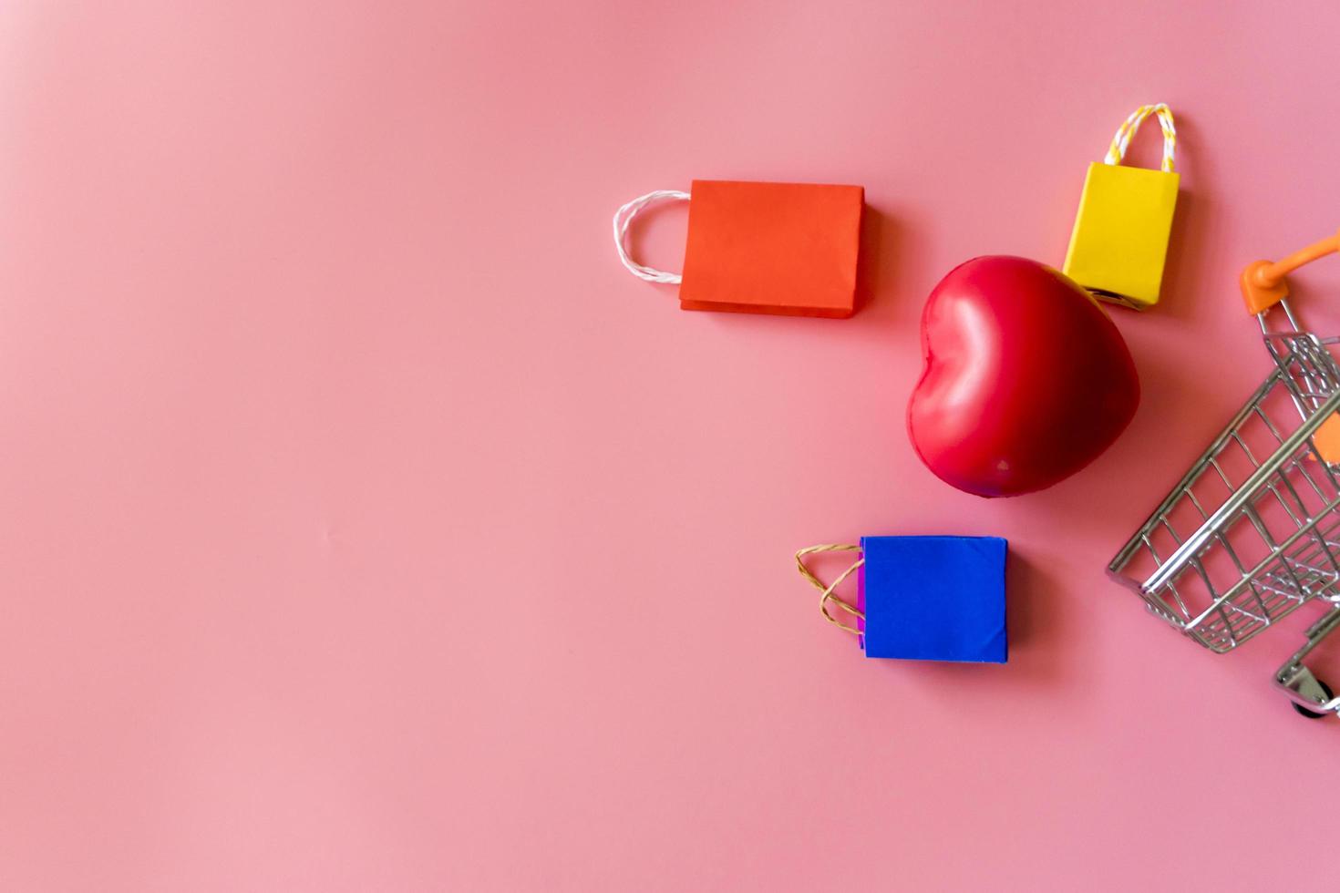 Minimal shoping online concept, Colorful paper shopping bag and trolley go down from floating pink background for copy space. Customer can buy everthing form home and the messenger will deliver. photo