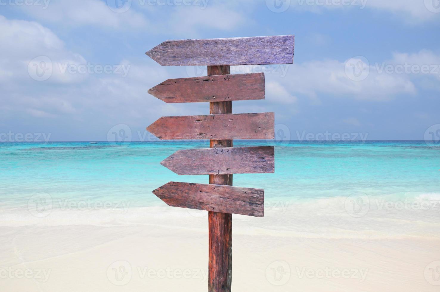 Wood signs for travel directions on the beach with sea and blue sky background. photo