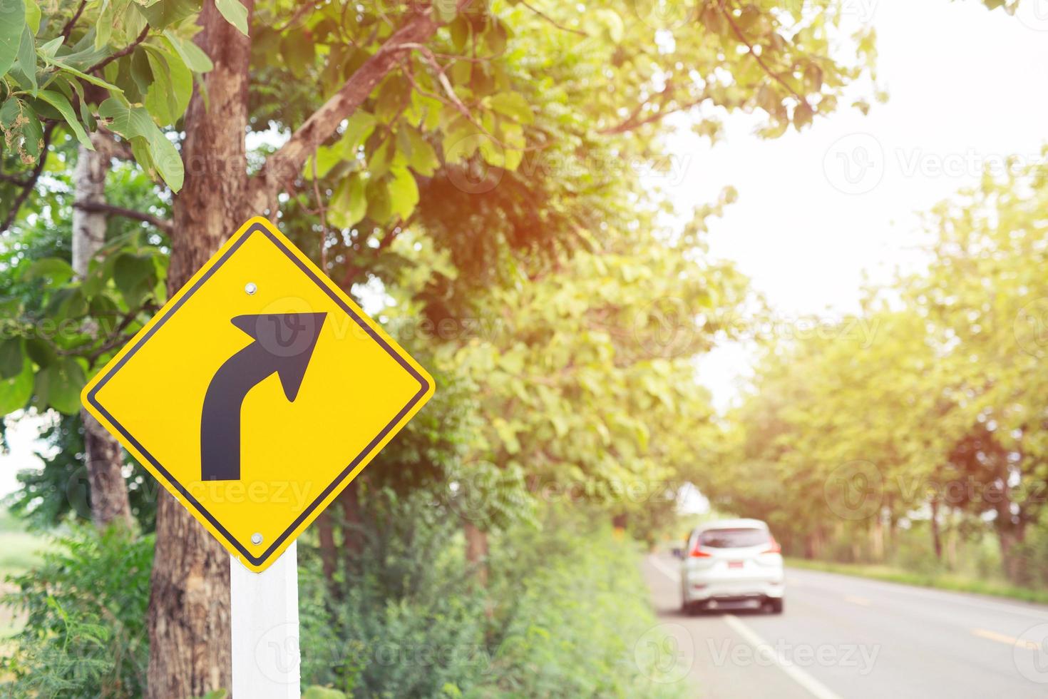 traffic sign placed beside along the road on route twisty winding slope. background driver car reduce speed and use a lower gear on country road. photo