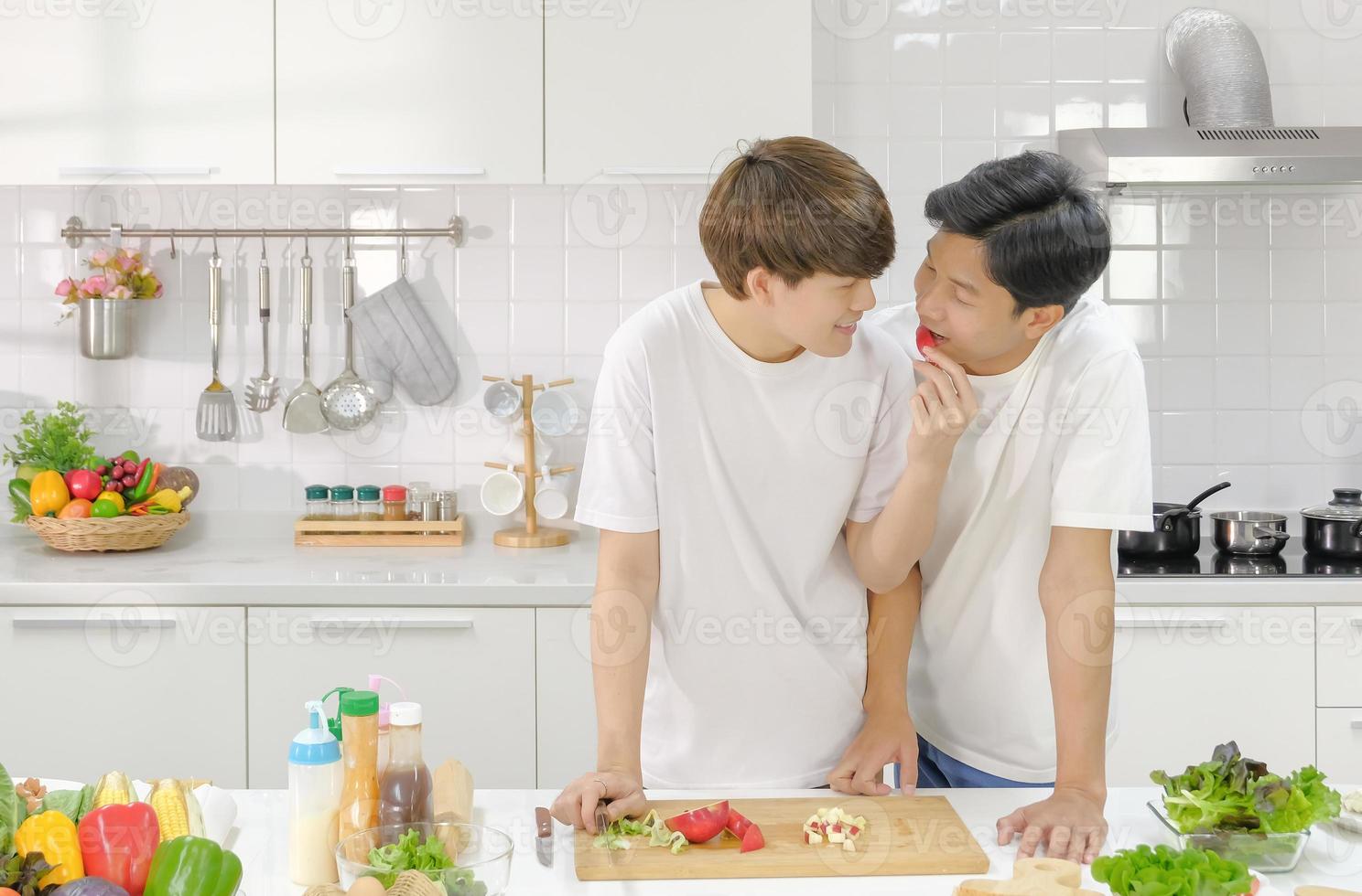 Intimate asian young male couple having romantic moment together in the kitchen during cooking. LGBT Domestic life concept. Selective focus. photo