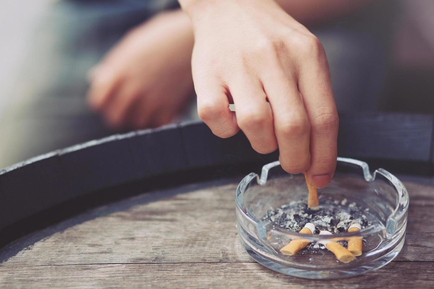 hombre sosteniendo fumando un cigarrillo en la mano. propagación del humo del cigarrillo. fondo oscuro foto