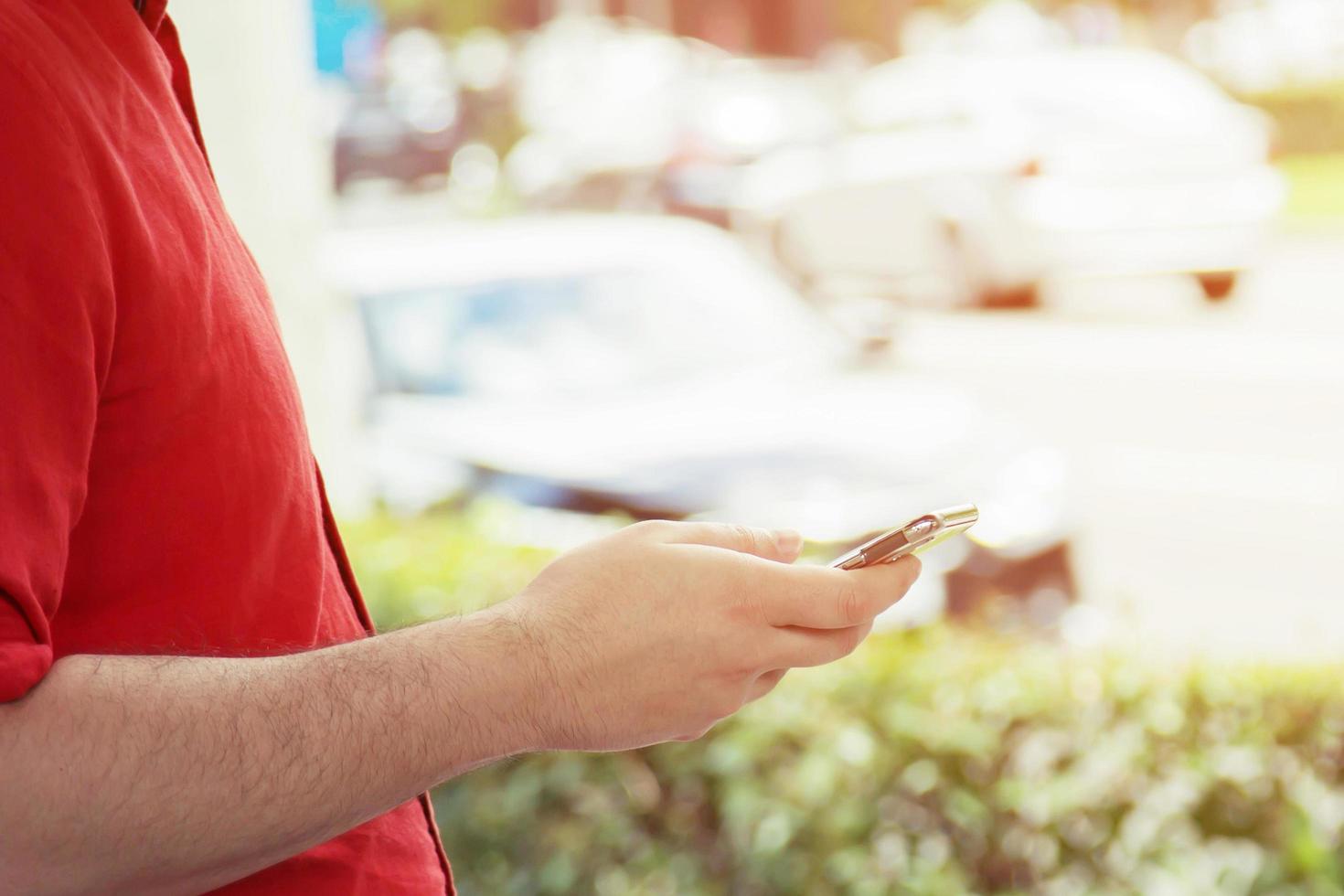 joven usa camisa a cuadros. cierre la mano usando el teléfono celular durante el descanso en el sofá. sentado viendo un mensaje en un teléfono inteligente móvil durante el descanso, relájese. enfoque suave. foto