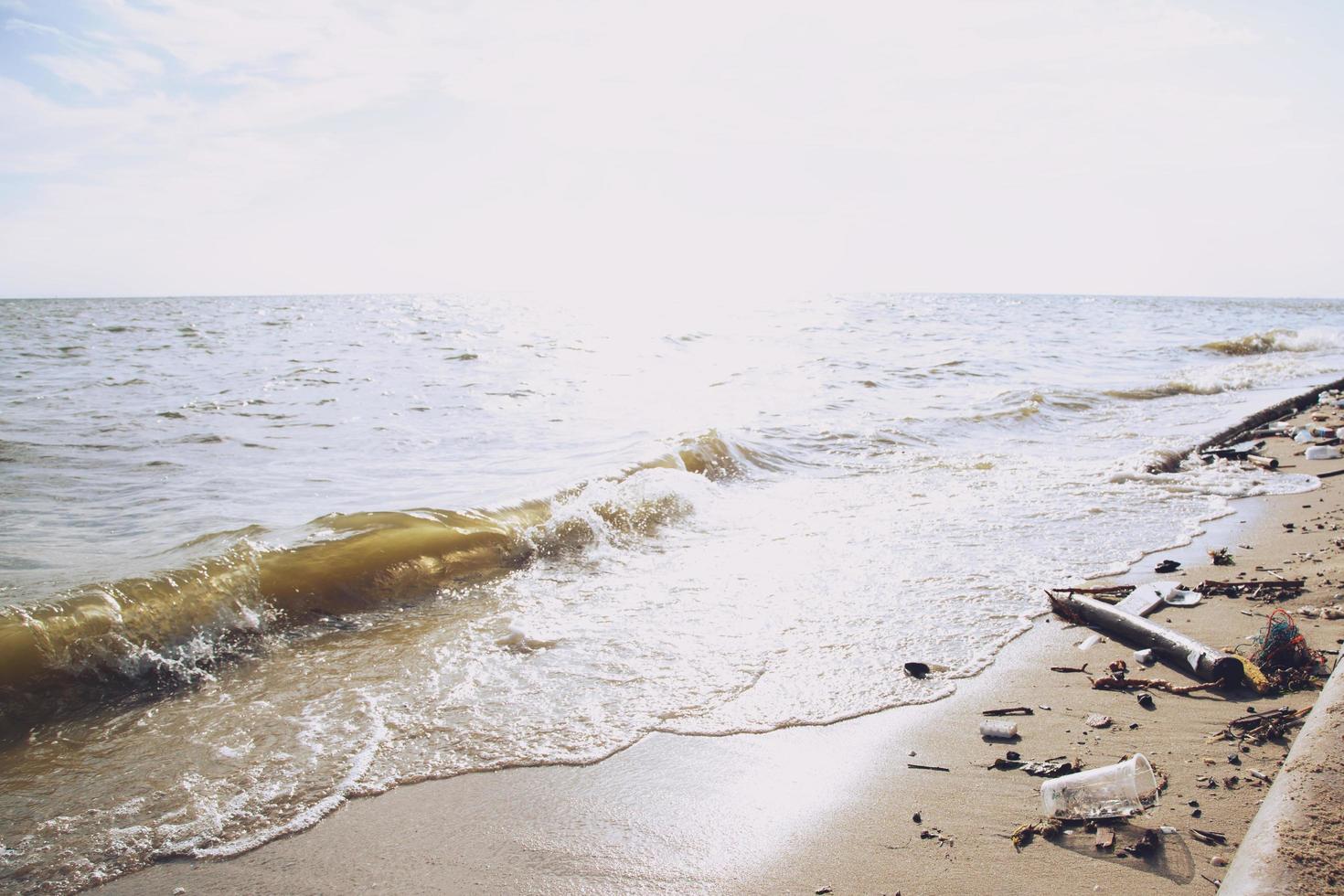 los desechos humanos tiran la botella de agua basura en la arena, hacen que el mar se pudra, lo que lleva al deterioro del mar. basura de playa daños ambientales que causan el calentamiento global. enfoque suave. foto