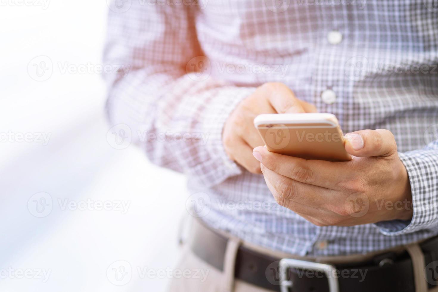 close up young man hand using on cell phone during rest on sofa living room. sitting in watching message on mobile smart phone during break relax. soft focus. photo