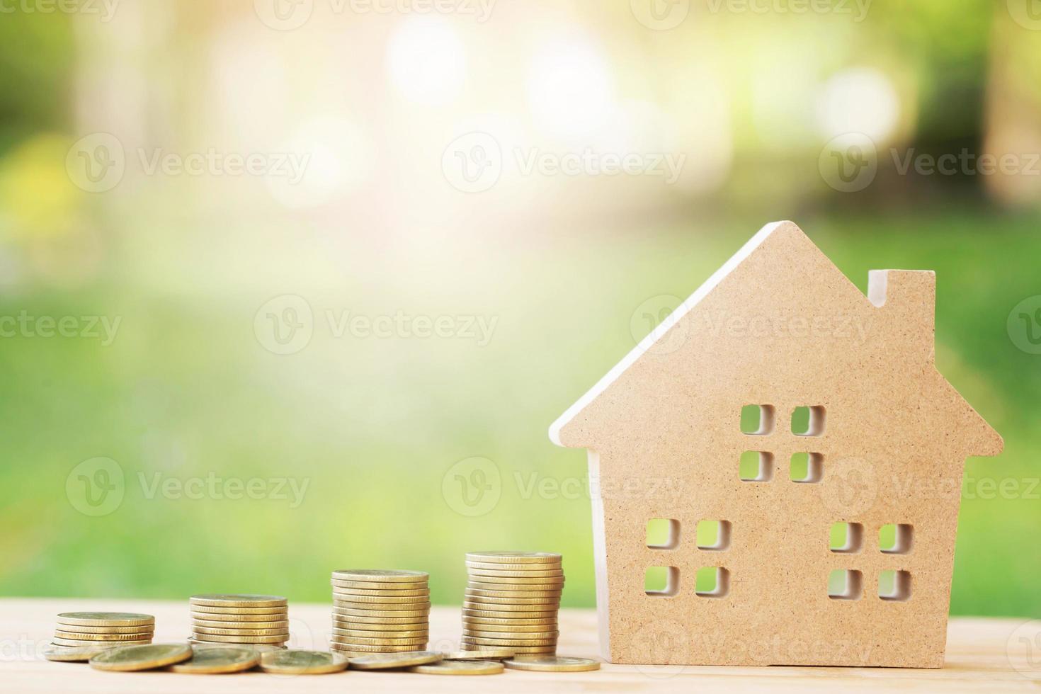 money coins stacked on each other in different positions and home in brown recycled paper model on the wooden table. Credit financial growing Loan to buy a house concept. Saving money. photo