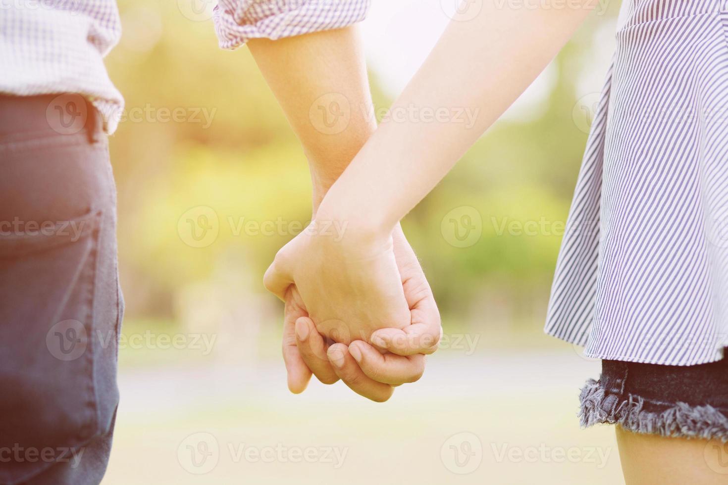 Couple lovers romantic holding hands towards the sun with bright sun flare in public parks, or close up view in a conceptual image first love adolescent young relationship. photo