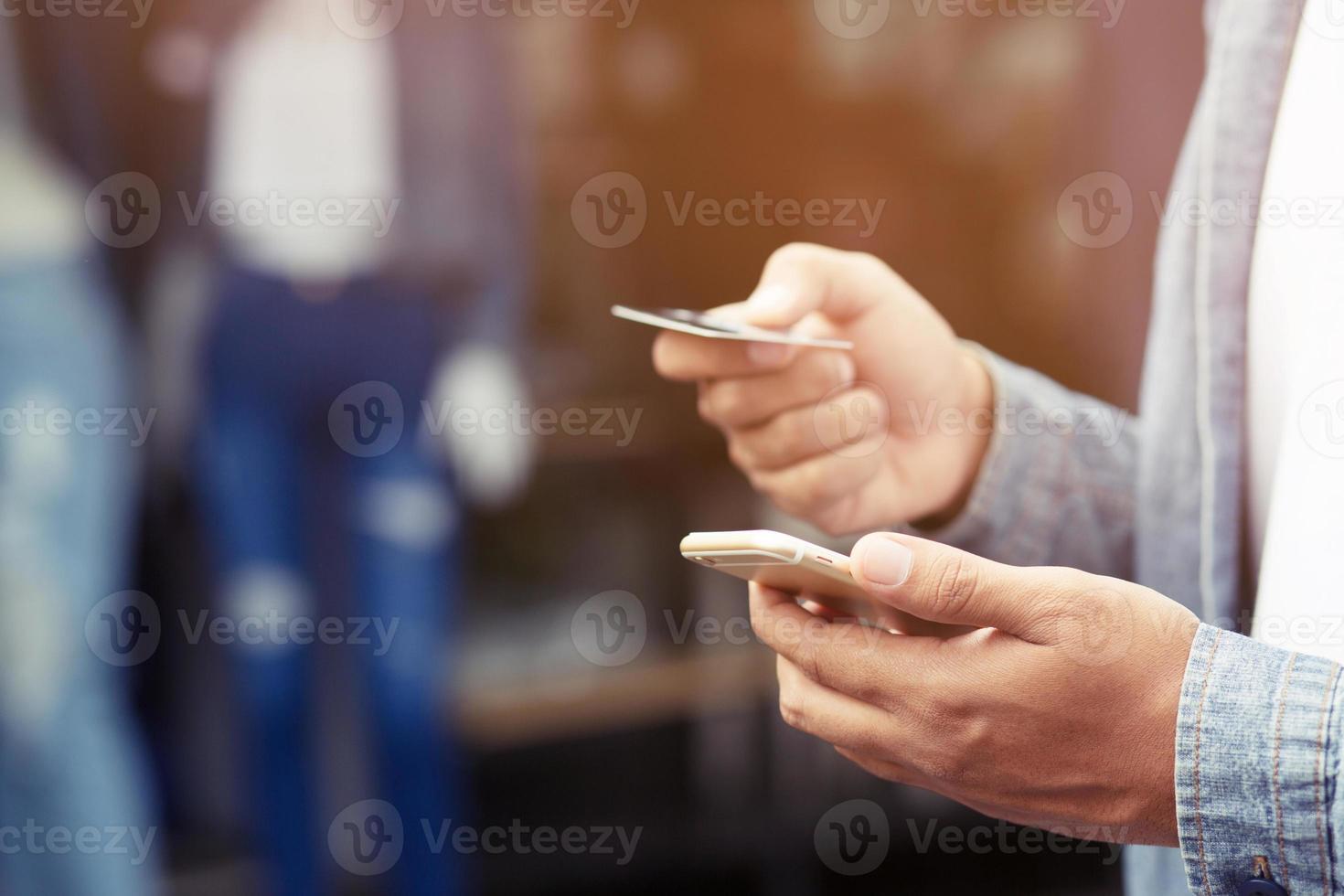 young male hands holding credit card and using mobile smart phone Standing in front of the clothing store. Online shopping purchase Sell or Payment. photo