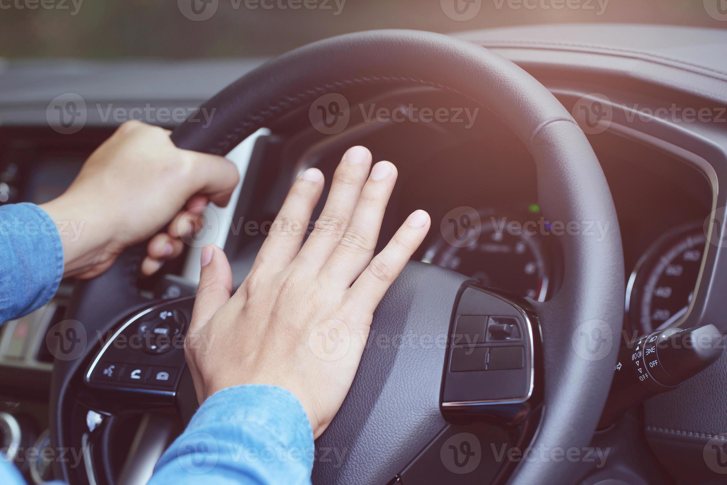 person pushing horn while driving sitting of a steering wheel press car