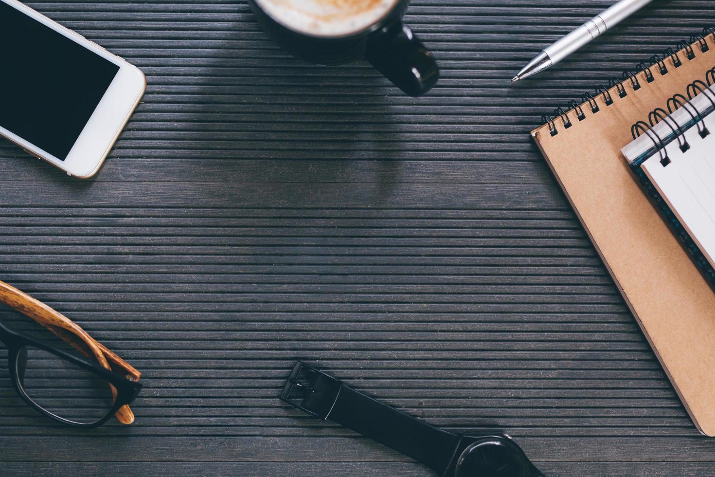 mesa de escritorio de oficina con libreta de libros, teléfono, suministros de equipo en el trabajo y taza de café. vista superior con espacio de copia. concepto para trabajar en una oficina moderna. foto