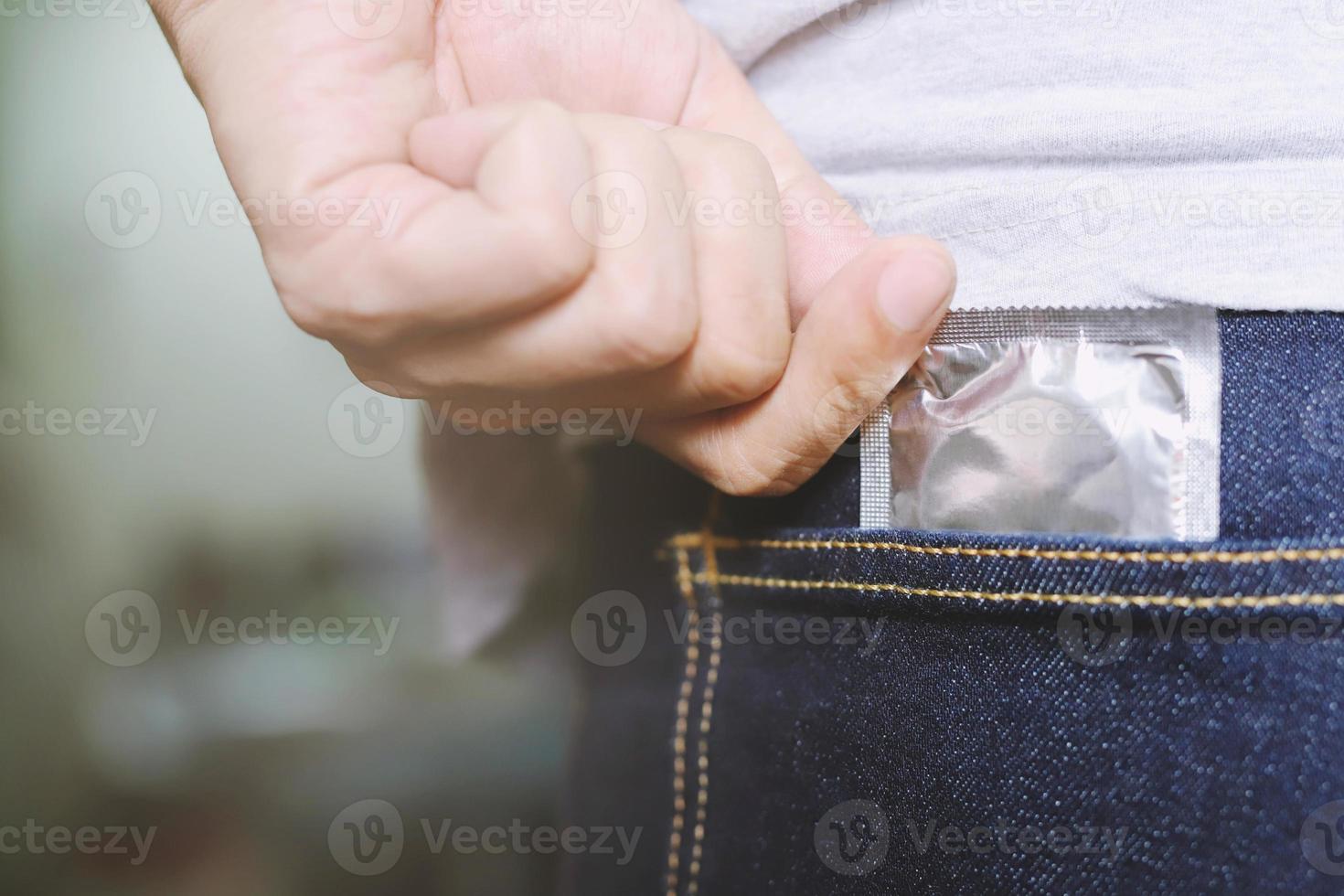 Young man jeans  back side pocket to carry condoms taking in hand pick condom from jeans safe sex concept on the bed Prevent infection Contraceptive control the birth rate or safe prophylactic photo