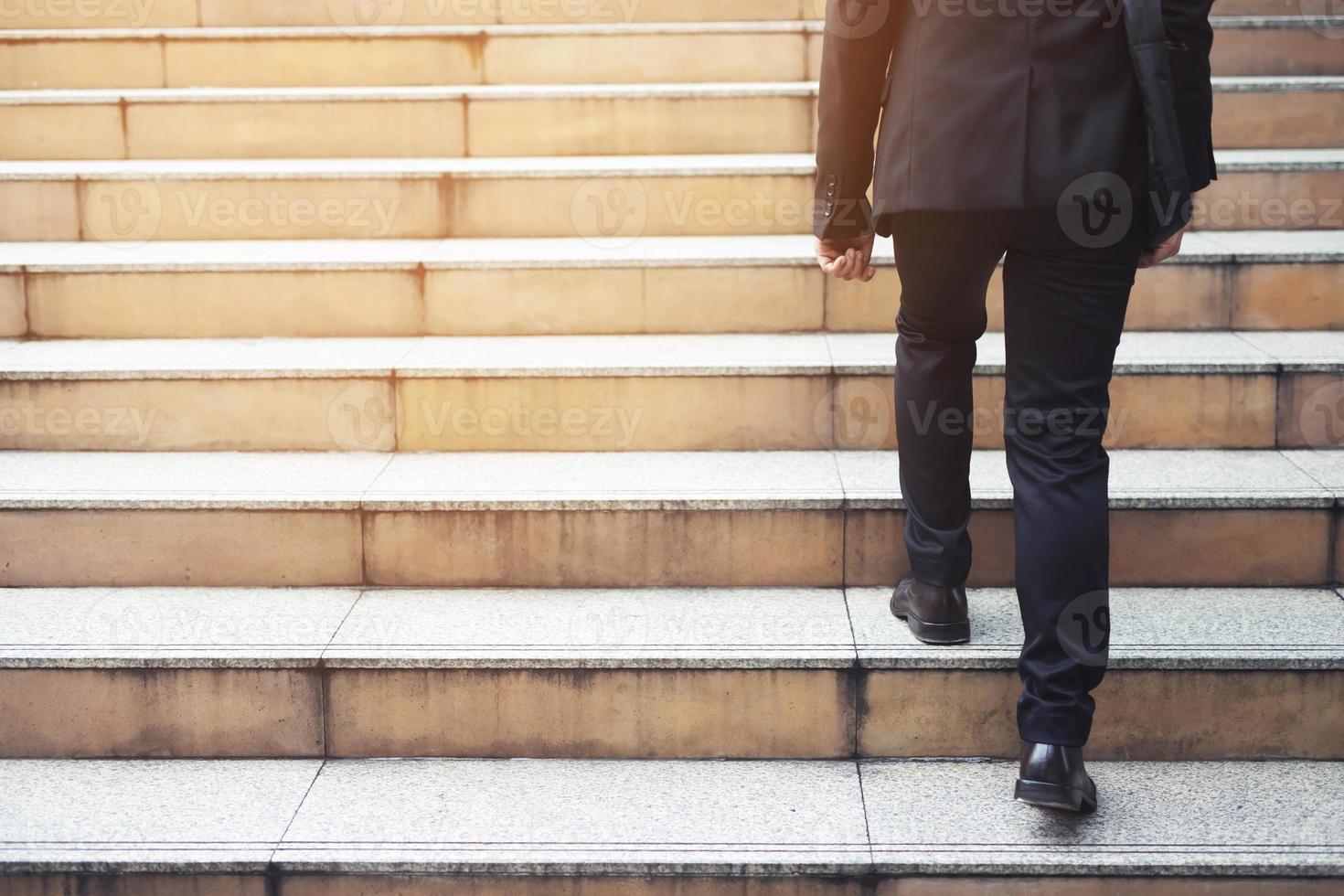 Ambitious businessman going up staircase. Back turned. photo