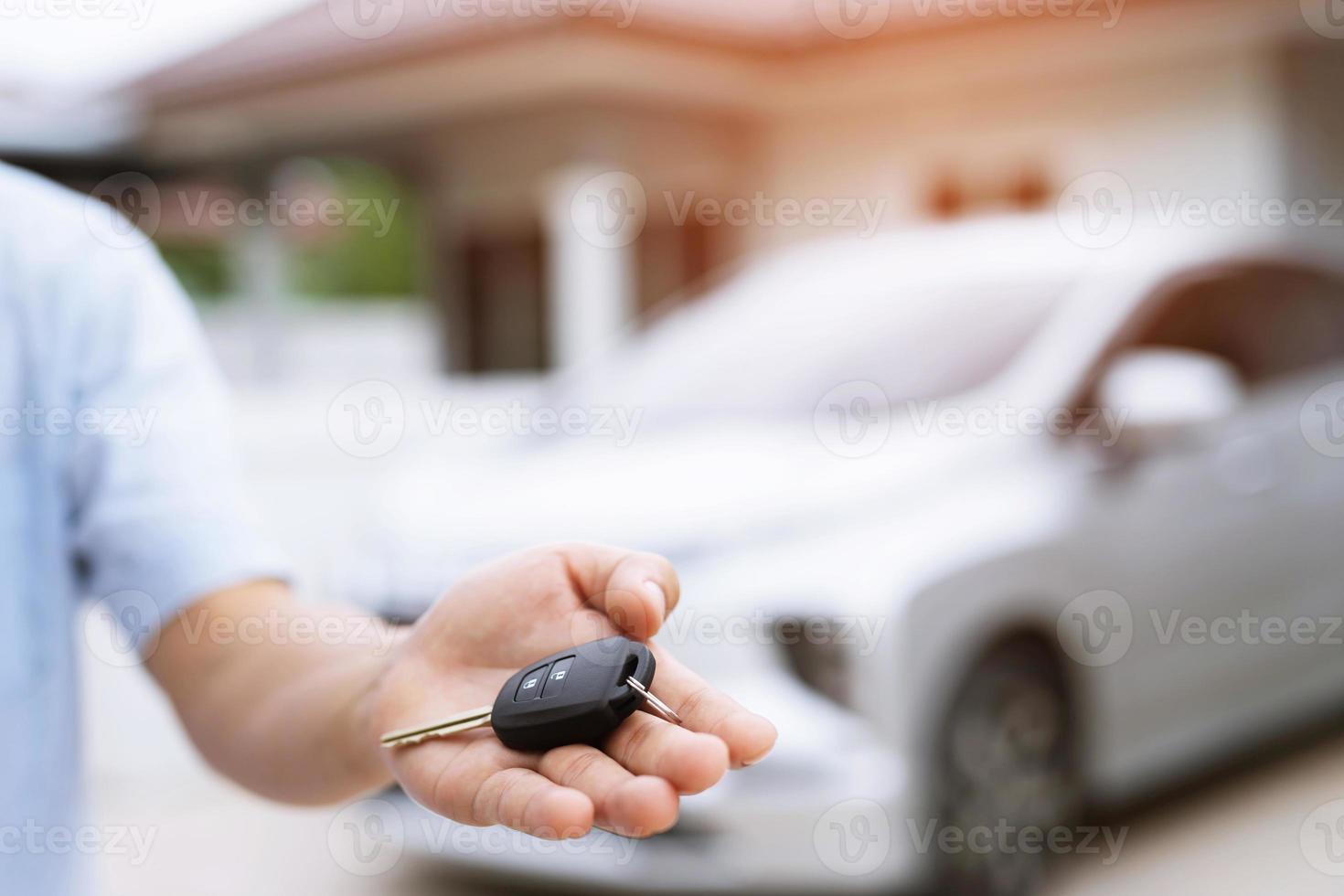 Car key, man handing over gives the car key to the other male on car an home background. Leave space to write a description of the message text. photo