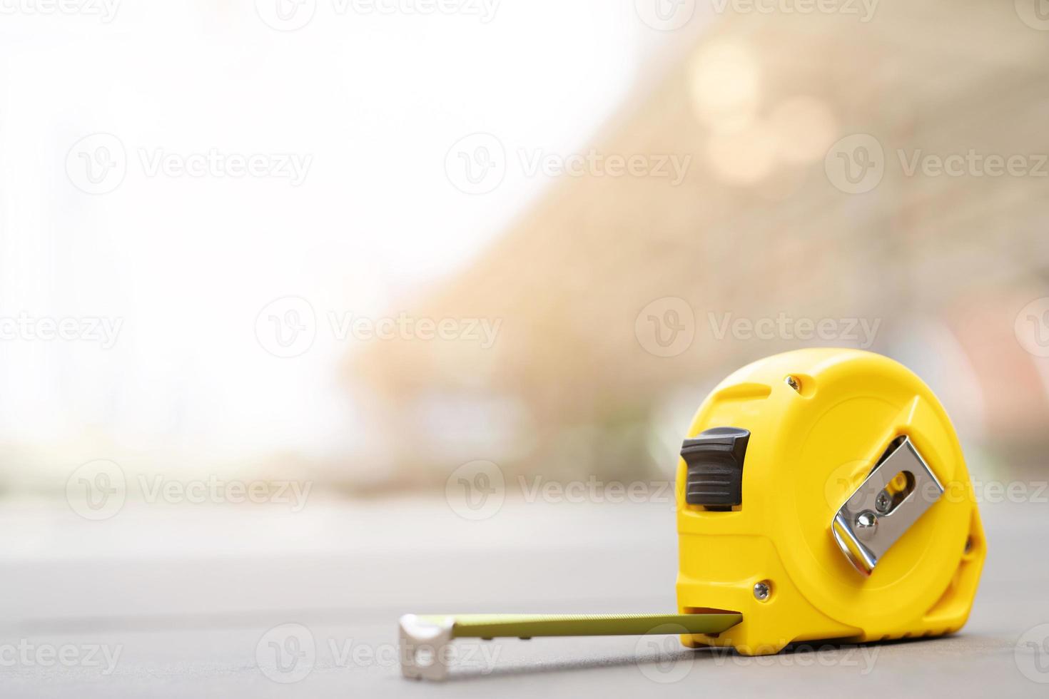 yellow tape measure background in the project at construction site building on concrete floor on city with sunlight. tool for workman as engineer or worker. photo