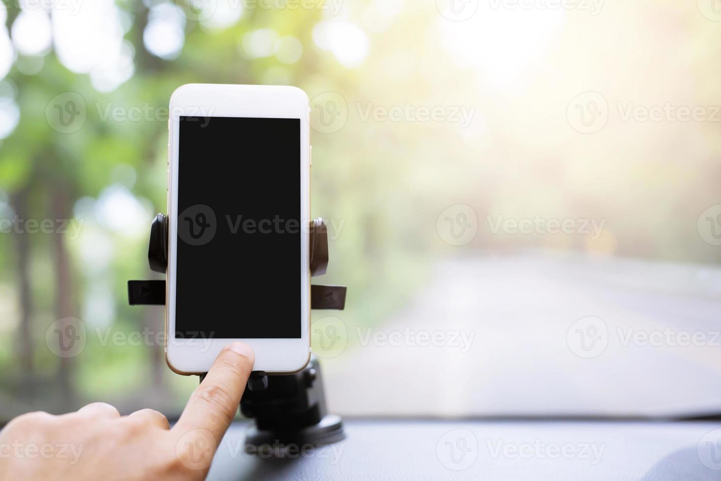 close up hand holding using mobile smart phone with black screen in car console front windshield holder stick. insert map gps navigation travel on the in the background of the dashboard. copy space. photo