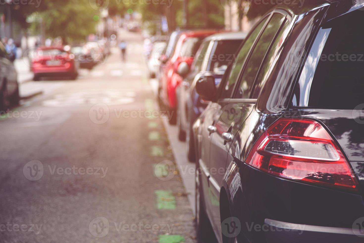 Car parking in large asphalt parking lot with trees, white cloud and blue sky background photo