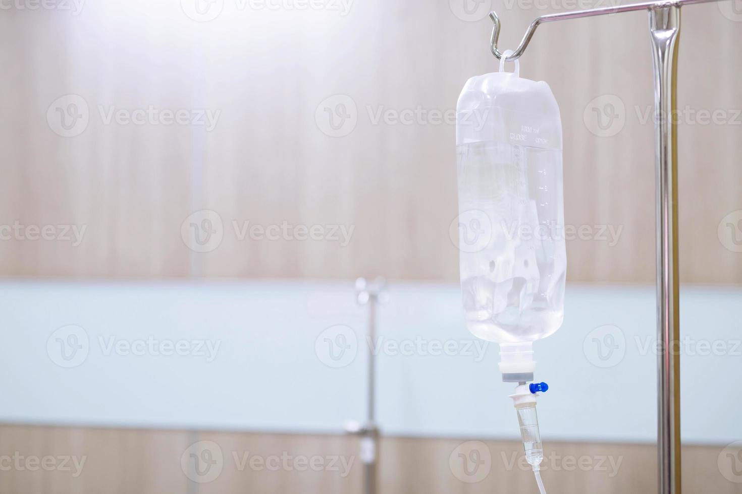 Equipo de infusión de bolsa de solución salina iv y botella en un poste. líquido gota intravenosa goteo salino lento habitación de hospital o clínica. concepto médico, shock de tratamiento de emergencia. Quimioterapia de atención de infusión de drogas inyectables foto