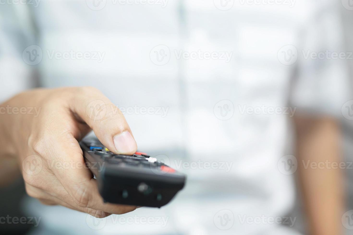 Man is watching TV with remote control in hand. photo