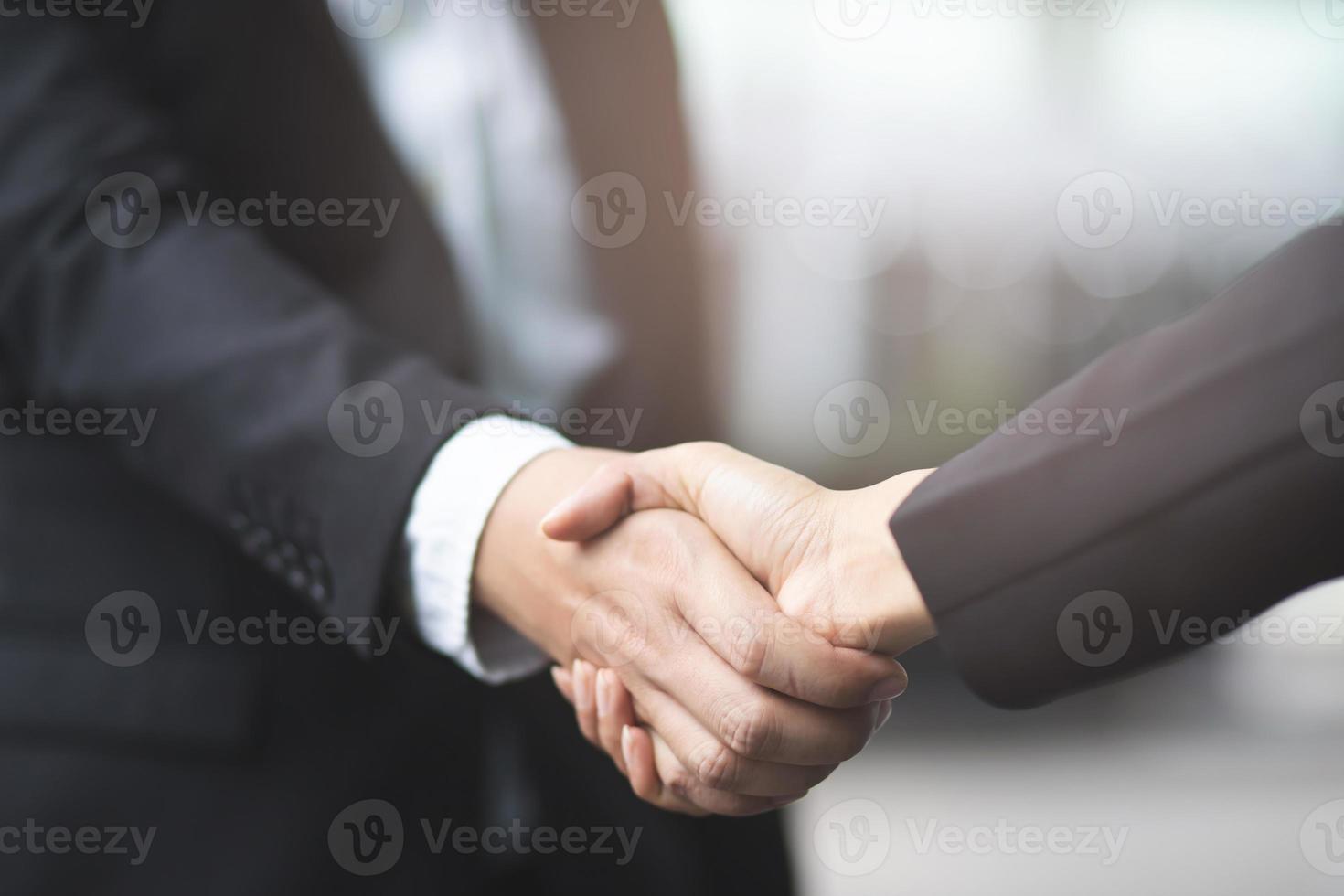 Two businessmen shake hands on the background of empty modern office, signing of a contract concept, photo