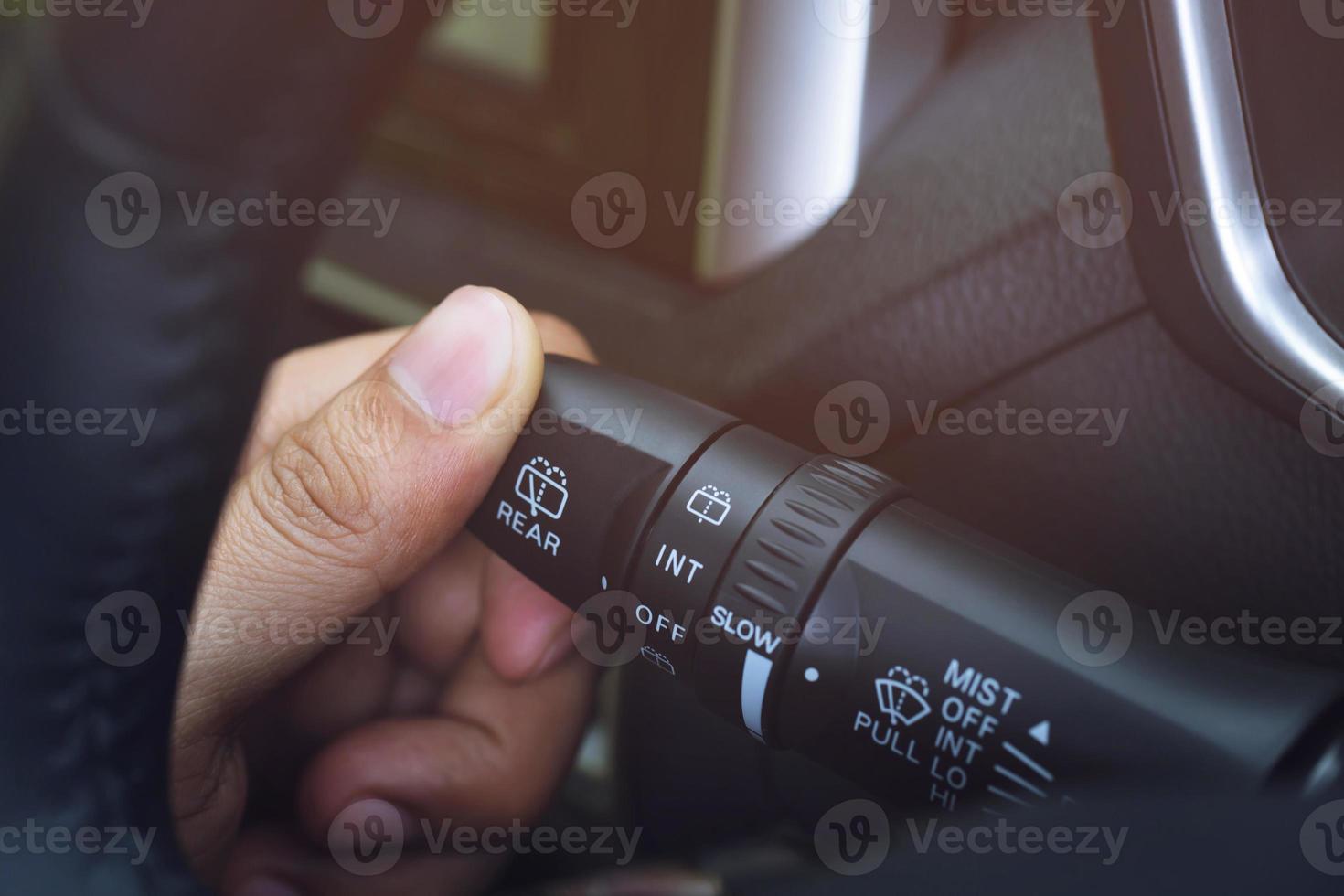 close up hand adjusting rain windscreen wiper knob control stick switch speed of screen front car. Adjustable wiper blade remove dirt from the windshield. Modern car interior detail. photo
