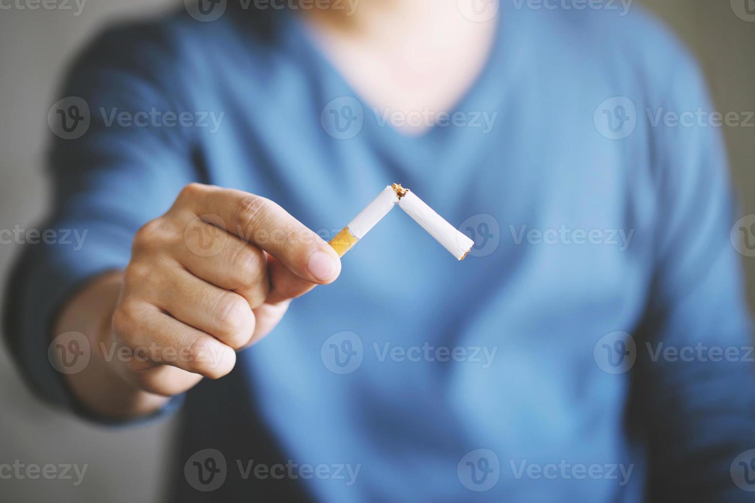 Portrait of man holding broken cigarette in hands. Happy man quitting smoking cigarettes photo