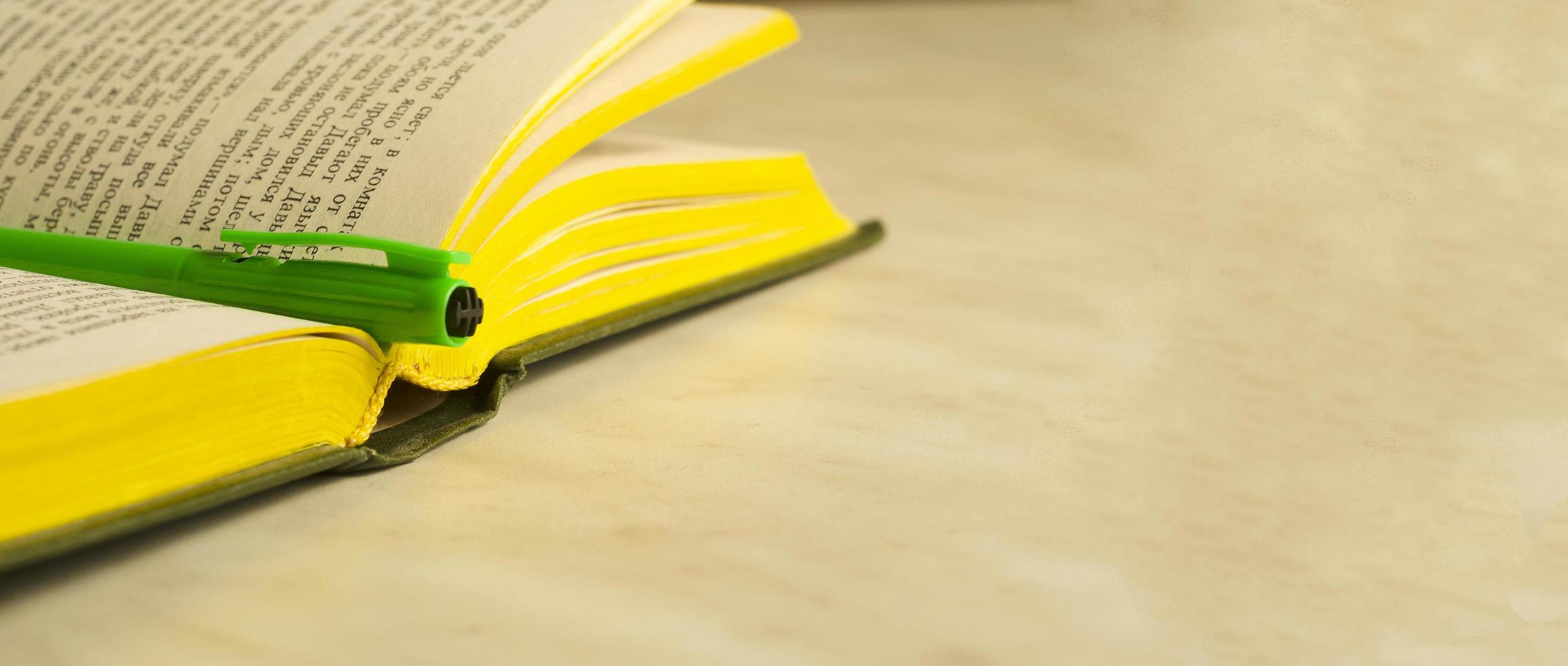 A green pen on an open book.The concept of education.Banner,copyspace. photo