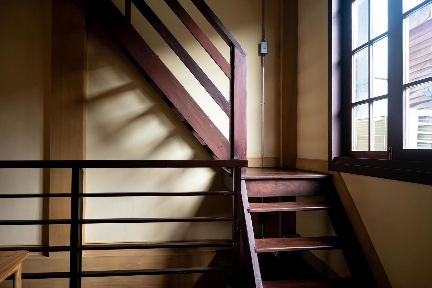 antigua escalera de madera junto a la ventana. sombra interior de la luz natural que pasa por la ventana. foto