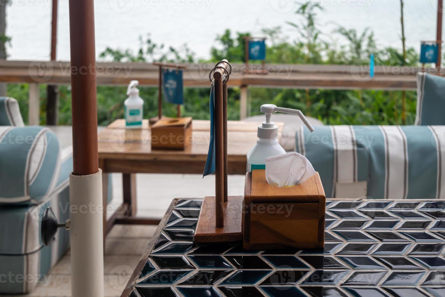 Dining table in the restaurant. Alcohol gel hand sanitizer served on the table in pandemic period. photo