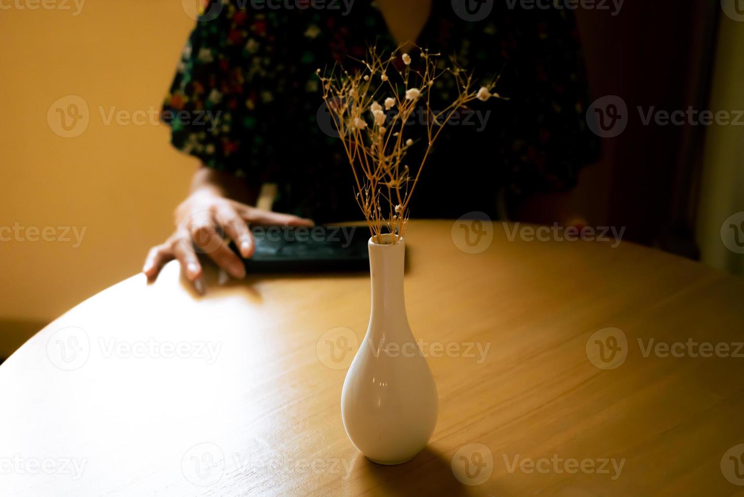 The girl in leisure time with her smart phone, vase in front of her, dramatic scene. photo