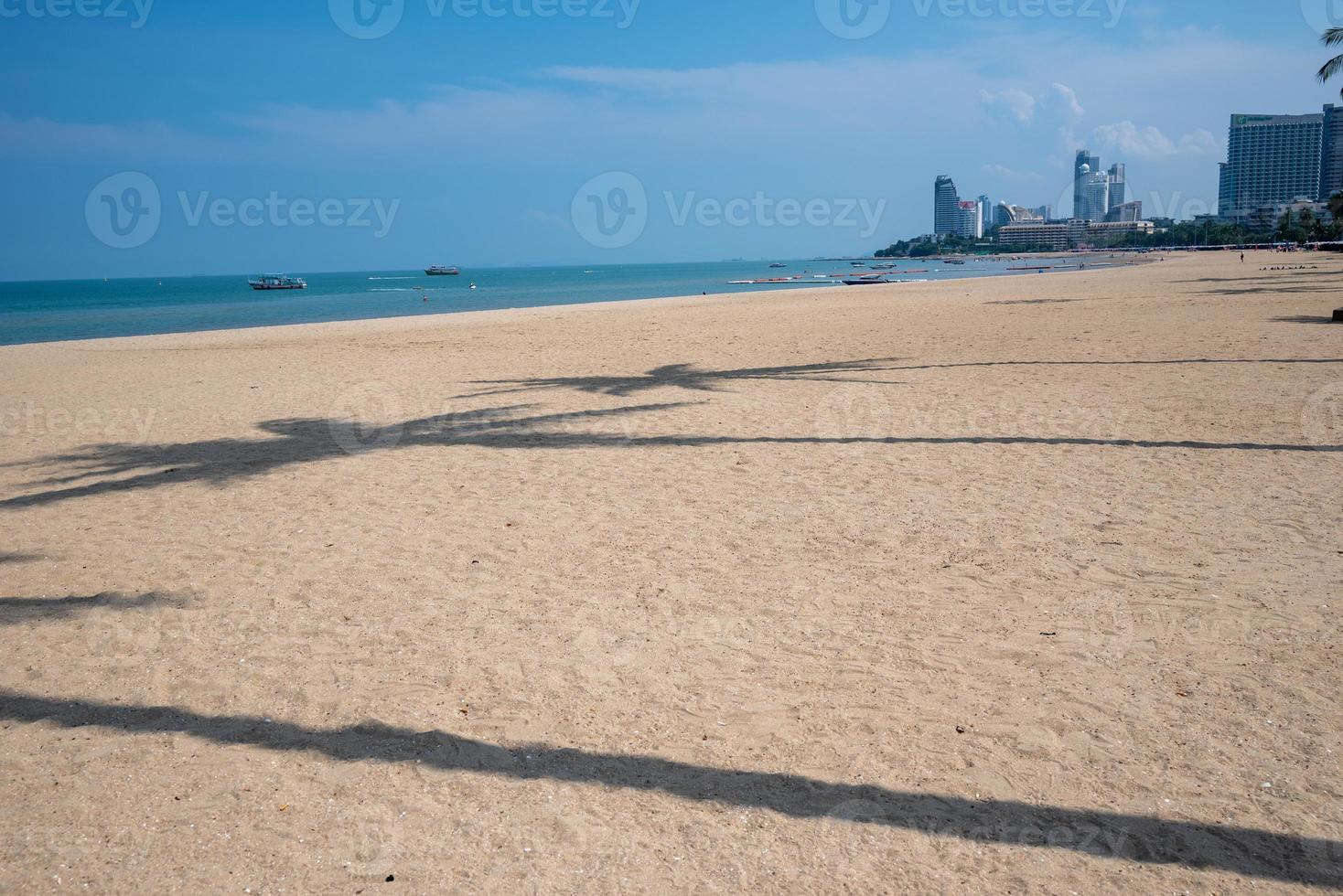 playa en el tiempo de la tarde. ciudad y edificio al otro lado. la sombra del árbol de coco yacía en la playa. foto