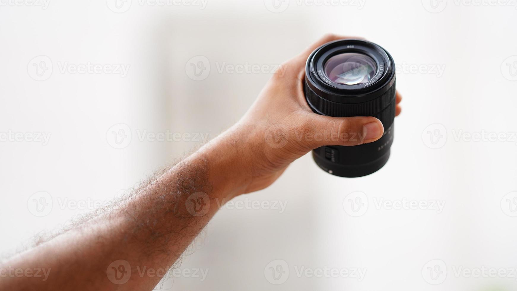 image of camera lens holding in hand vertically. photo