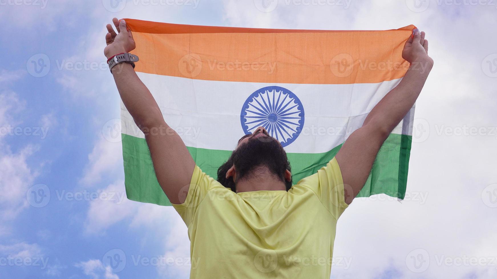 joven ondeando la bandera nacional india sobre el hermoso fondo del cielo foto