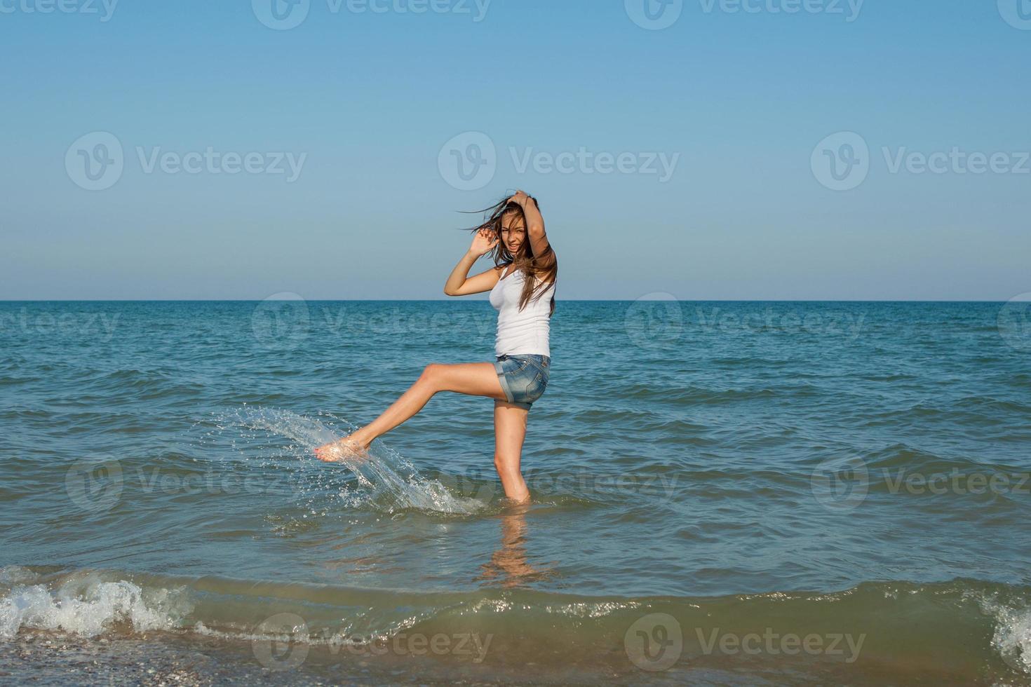 young girl splashing the water in the sea photo
