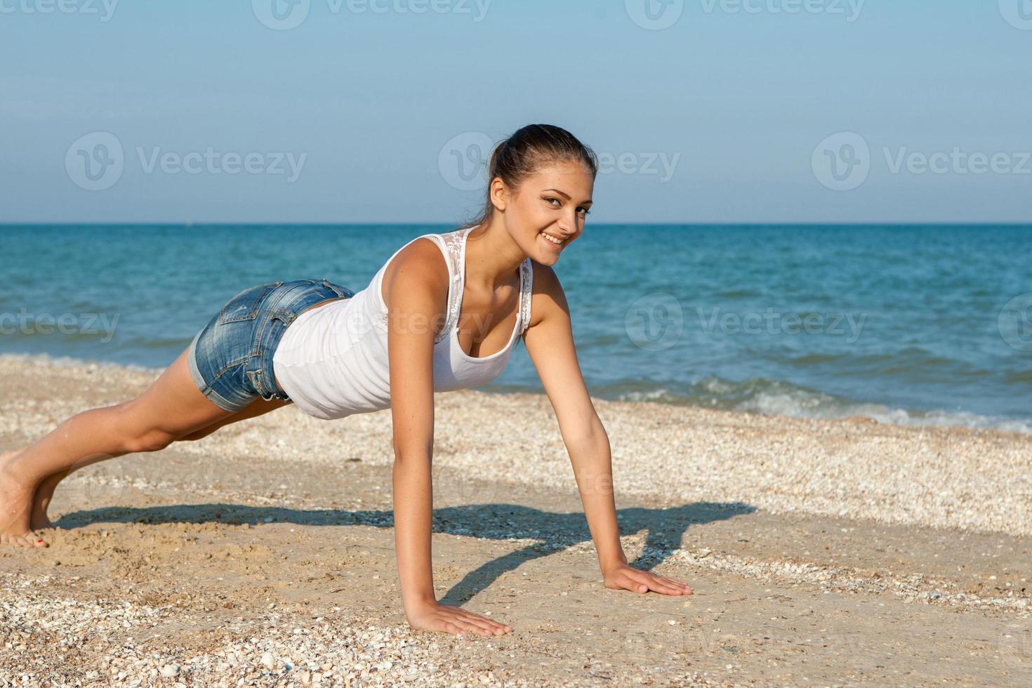 mujer joven practicando yoga o fitness en la orilla del mar foto