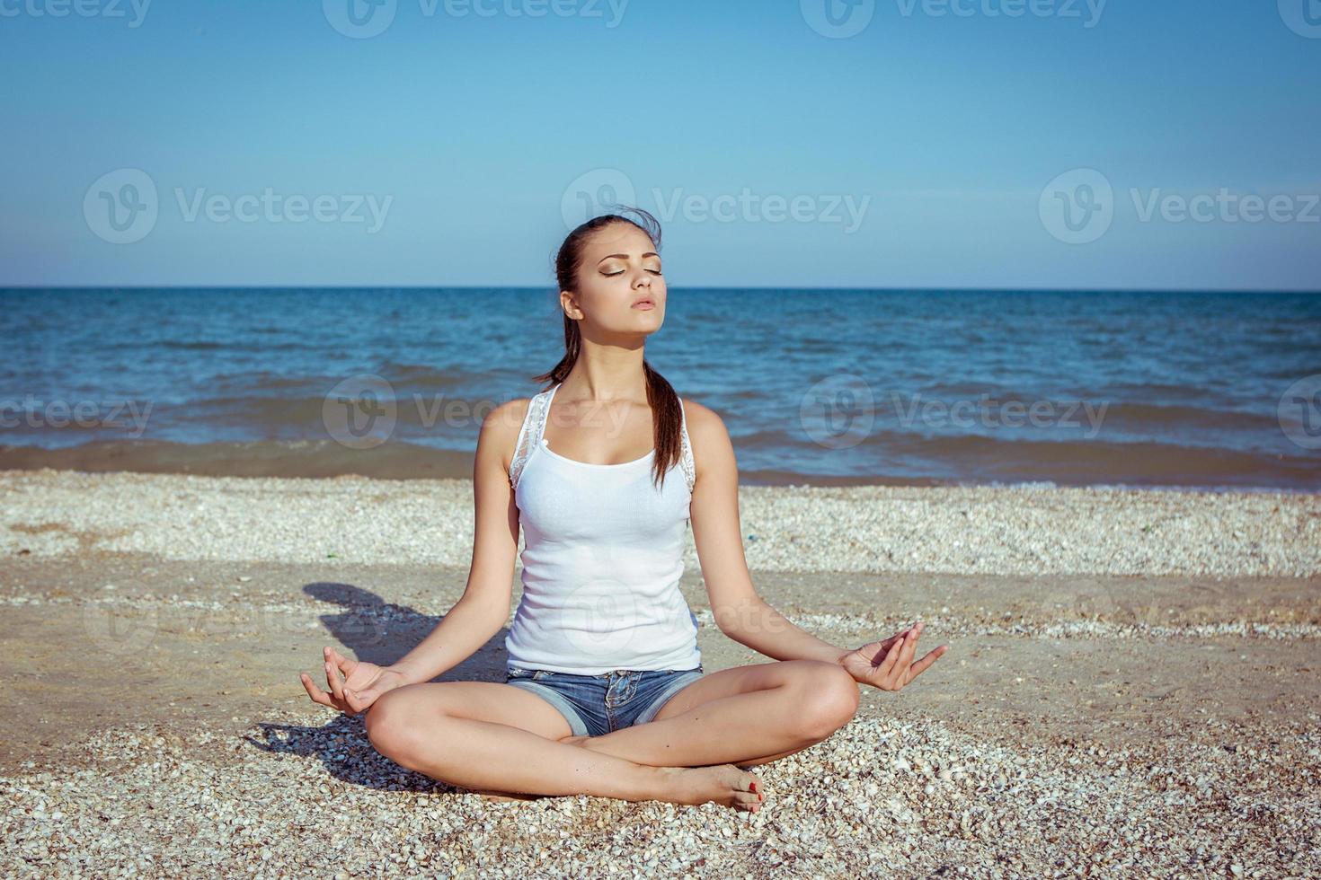 young woman practicing yoga or fitness at seashore photo