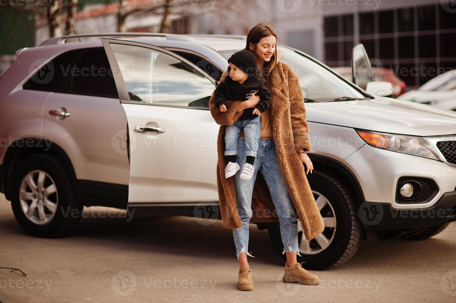 Young mother and child stand near they suv car. Safety driving concept. photo