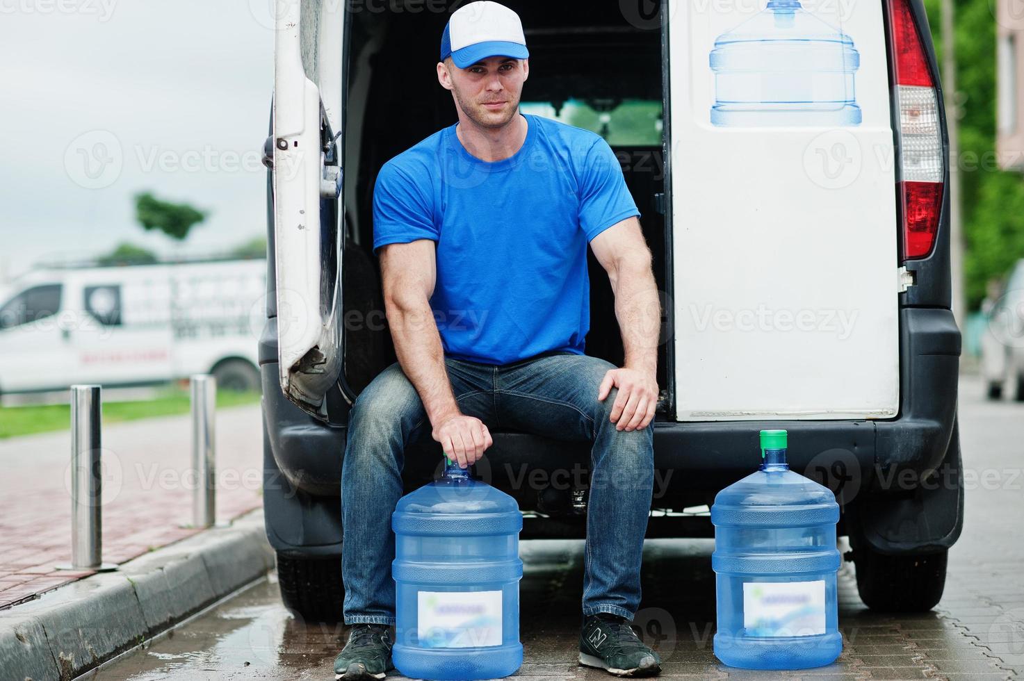 Delivery man in front cargo van delivering bottles of water. photo
