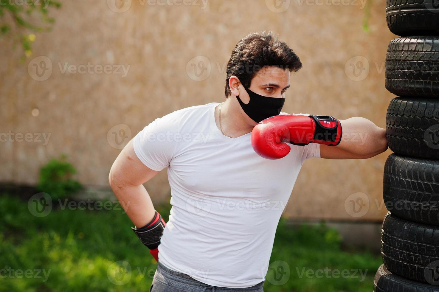 Portrait sports arabian boxer man in black medical face mask boxing outdoor during coronavirus quarantine. photo