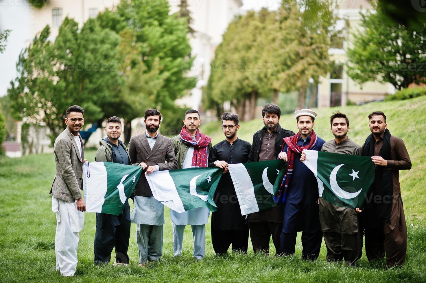 grupo de hombres paquistaníes vestidos con ropa tradicional salwar kameez o kurta con banderas de pakistán. foto